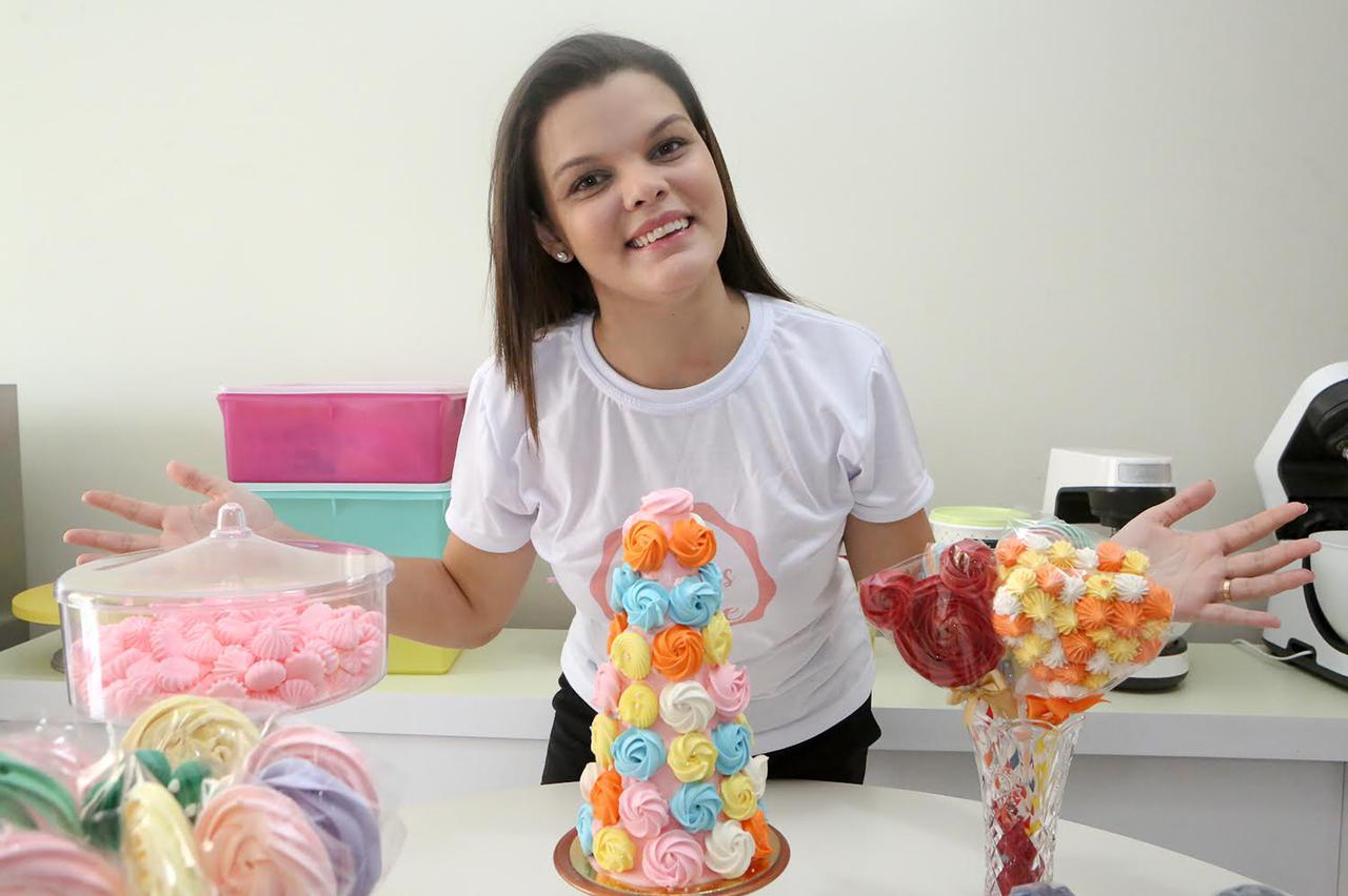 jamile farias posa para a foto diante de uma mesa onde estão os suspiros que ela faz